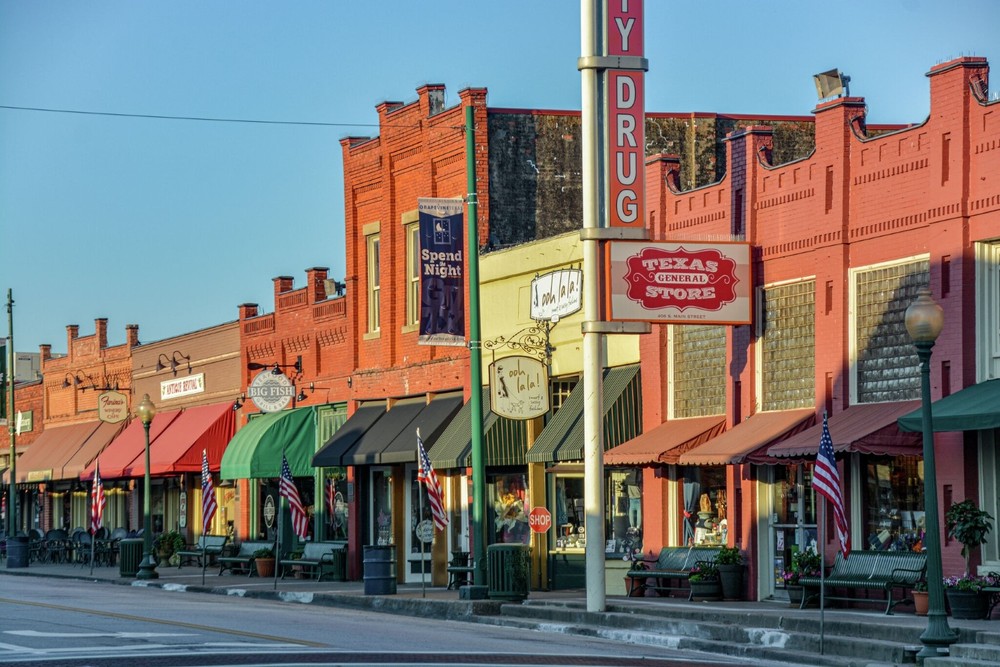 streetview of a line of stores and restaurants in Grapevine, TX. The street has a lot of character and the buildings colors are red, green, yellow. 