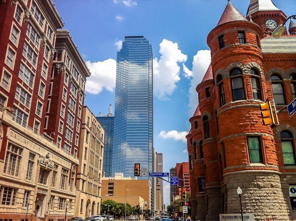 View of the 6th Floor Museum and adjacent red buildings during the JFK Tour, with a tower museum nestled between. Explore the iconic location of the JFK assassination, featuring historical landmarks and exhibits
