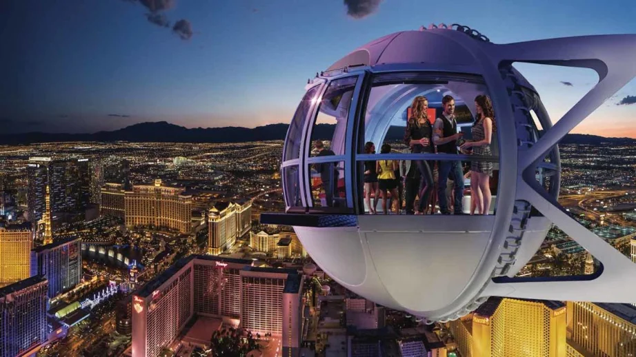 People enjoying a nighttime ride in a High Roller pod in Las Vegas, with a view of the city skyline and brightly lit buildings below