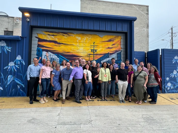 Group of people on a food tour in Deep Ellum, Dallas, organized by Food Tours of America, posing in front of a mural.