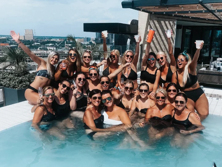 Group of women in swimsuits celebrating a bachelorette party in a rooftop pool in Texas