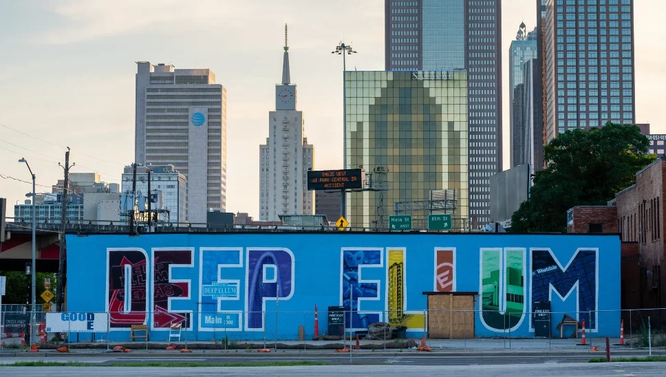 Deep Ellum mural in Dallas with the city skyline in the background, showcasing the vibrant and artistic neighborhood