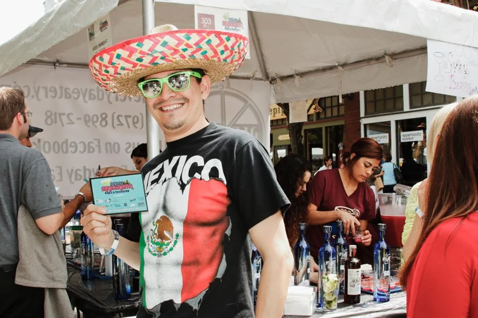 Man enjoying the Dallas Margarita Festival at Ferris Wheelers Backyard and BBQ, wearing a sombrero and holding a margarita sampling card