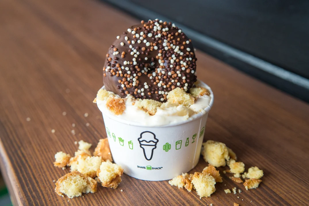 Strawberry Frosted Donut Shake from Shake Shack, featuring donut-flavored frozen custard topped with a chocolate-frosted donut, rainbow sprinkles, and crumbled cake pieces