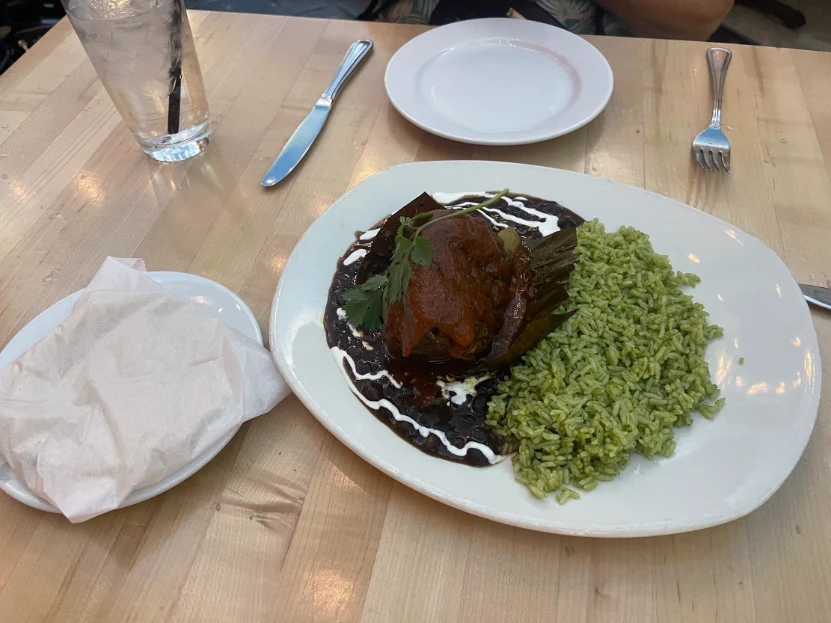 Mexican dish with green rice and a tamale covered in sauce at a restaurant in Downtown Las Vegas.