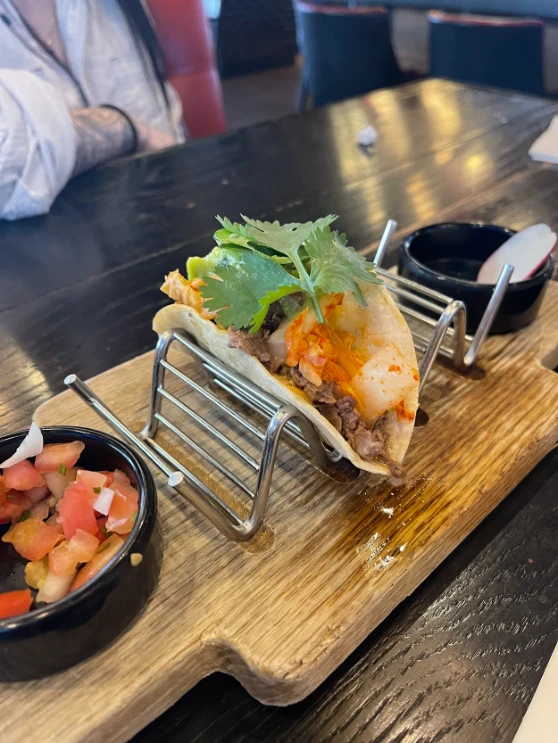 Taco topped with cilantro and kimchi, served with sides of pico de gallo and sauce, at a restaurant in Downtown Las Vegas.