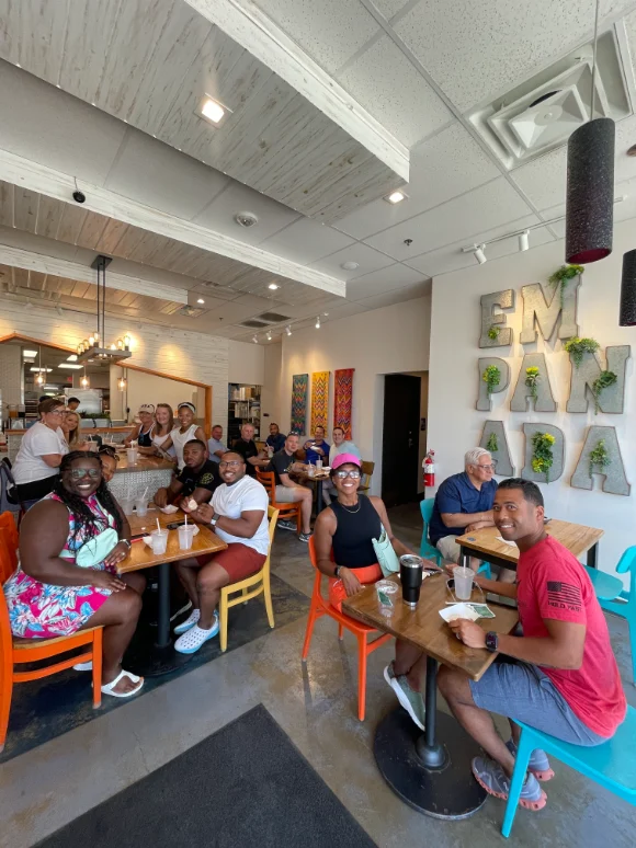 Group of people enjoying a meal at the Empanada House in Dallas, seated at colorful chairs and tables in a bright, welcoming interior.