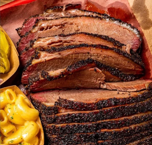 Slices of smoked brisket accompanied by macaroni and cheese and pickles, taken during a food tour in the Stockyards, Fort Worth.