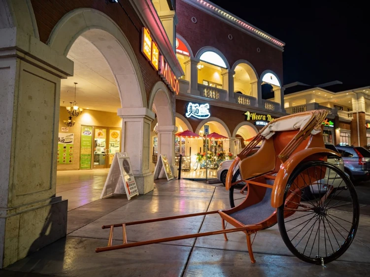 Nighttime view of Chinatown Plaza in Las Vegas, featuring a decorative rickshaw and illuminated storefronts.