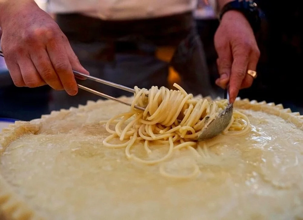 Spaghetti being mixed in a large wheel of cheese at a restaurant on the Las Vegas Strip.